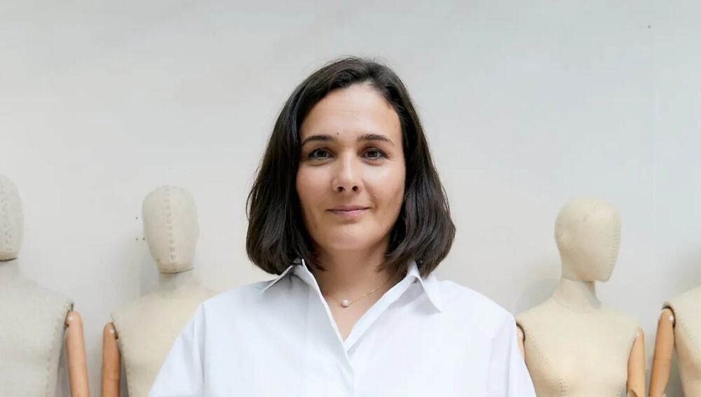 Adriana Dom&iacute;nguez con camisa blanca junto a unos maniqu&iacute;es de costura