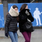 Dos personas se protegen del frío en una céntrica calle de Madrid