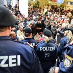 Policías forman un cordón frente a los cientos de refugiados que esperan la llegada de más trenes con dirección a Alemania en la estación de Salzburgo (Austria)