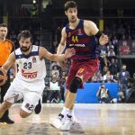 El base escolta del Real Madrid Sergio Llull (i) lucha con el pívot croata del FC Barcelona Lassa Ante Tomic, durante el partido