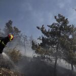 Un bombero trata de sofocar un incendio en el suburbio de Karea en Atenas, Grecia.