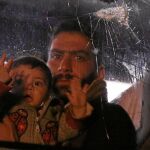 Un civil de la ciudad siria de Duma sostiene en brazos a un bebe en el autobús que le trasladará a Alepo