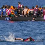Un sirio nada hacia la orilla tras averiarse la barca llena de refugiados en la que viajaba hacia la isla griega de Lesbos