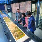 La directora general adjunta de la Fundación Bancaria 'la Caixa' Elisa Durán (c), el subdirector del museo de Nankin, Qizhi Wang (d) y el director del Nomad Exhibitions, Tim Pethick (i) observan la pintura en rollo horizontal "Mujeres ociosas de una dinastía antigua"que mide 13,5 metros de longitud