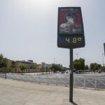 Turistas pasan junto a un termómetro de Sevilla testigo del intenso calor