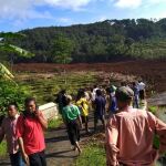 Varias personas permanecen cerca del lugar donde se produjo un alud de tierra en Brebes, en la isla indonesia de Java, hoy