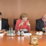 La canciller alemana, Angela Merkel (centro), habla con el jefe de la cancillería, Peter Altmaier (dcha), junto a su ministro de Economía, Sigmar Gabriel.