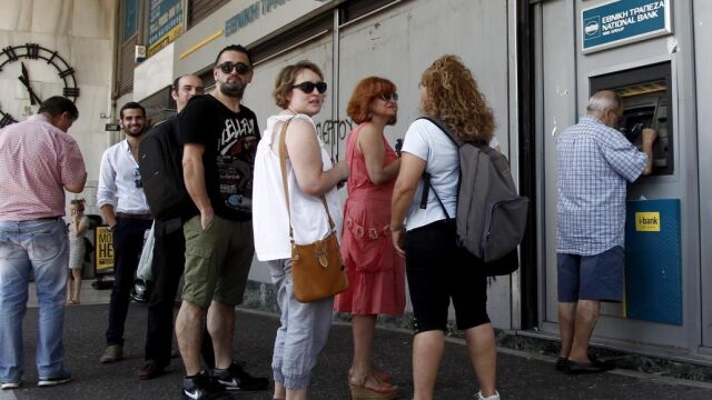 Atenienses hacen cola para retirar dinero de un cajero automático en una sucursal del Banco Nacional de Grecia, en Atenas