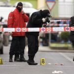 Varios miembros de la Ertzaintza fotografían el lugar de la localidad de Arrasate-Mondragón (Guipúzcoa) en el que el ex concejal socialista Isaías Carrasco fue asesinado