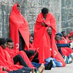 Inmigrantes protegidos con mantas de Cruz Roja esperan a ser atendidos en el puerto de Tarifa (Cádiz)