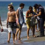 Un policía nacional inspecciona el bolso de un bañista