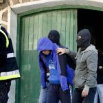 Varios agentes de la policía trasladan a uno de los presuntos miembros de Segi, la organización juvenil ilegalizada de ETA, detenido en la localidad guipuzcoana de Astigarraga