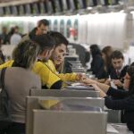 Unos pasajeros se informan esta mañana en Barajas sobre su vuelo