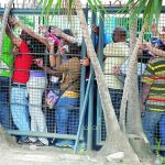 Venezolanos hacen cola ayer a la entrada de un supermercado de Caracas junto a una valla