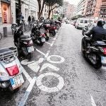 Un usuario de motocicleta circulando por la calzada y una zona de estacionamiento de motos en Valencia