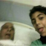 El joven saca la lengua para posar junto al cadáver de su abuelo