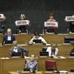 Los parlamentarios de EH Bildu en la Cámara foral han exhibido carteles con la palabra "Tortura"durante la intervención hoy en el pleno de la portavoz del PPN, Ana Beltrán