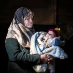 Umm Azem posa con su nieto en brazos en la tienda que ocupa con su familia en el valle de La Bekaa