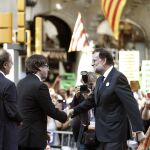 El presidente del Gobierno Mariano Rajoy (d) saluda al presidente catalán Carles Puigdemont (i) durante la manifestación de ayer en Barcelona