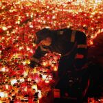 Un policía rumano ordena las velas encendidas en tributo de las víctimas de un incendio en una discoteca, el lunes 2 de noviembre de 2015, en Bucarest
