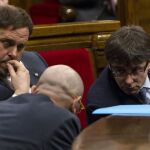 El presidente de la Generalitat, Carles Puigdemont, conversa con el conseller de Asuntos Exteriores, Raül Romeva (i), ante el vicepresidente, Oriol Junqueras.