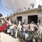 Residentes agitan banderas sirias durante un encuentro con una columna ruso con ayuda humanitaria