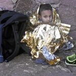 Un niño se abriga con una manta térmica tras desembarcar ayer con un pequeño bote en la isla griega de Lesbos