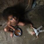 Ana Luisa de 3 años, come un plato de arroz en la puerta de su casa, en el barrio Capotillo, de la capital Dominicana donde el índice de desnutrición infantil es muy elevado