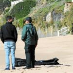 Agentes de la Guardia Civil ante el cadáver de un inmigrante en la playa de Caños de Meca, en la localidad gaditana de Barbate. Doce siguen sin aparecer