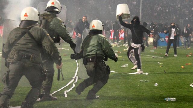 Agentes antidisturbios griegos tratan de controlar a los aficionados que invadieron el campo de fútbol