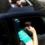 Dos jóvenes hablan por teléfono dentro de un coche