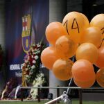 Unos cuantos globos de color naranja con el número 14 que han sido dejados por un aficionado ante la puerta de tribuna del Camp Nou, en recuerdo del primer aniversario de la muerte de Cruyff