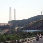 Un grupo de motocicletas pasa junto a las chimeneas de la central eléctrica de Hsieh-ho en Keelung, Taiwán