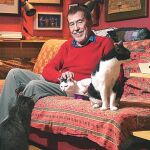El escritor, junto a sus gatos en el sofá donde se sienta a leer y los tres se le tumban encima