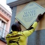 Un hombre coloca un placa durante la concentración convocada por el Sindicato de Manteros esta tarde en la plaza de Nelson Mandela, en Madrid, en recuerdo a Mame Mbaye