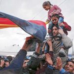 Un grupo de refugiados ondea una bandera alemana en la frontera entre Grecia y Macedonia, cerca de Idomeni