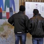 Dos asilados sirios miran el tablón de anuncios en el centro de refugiados de Naerboe (Noruega)