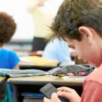 Un estudiante utilizando su teléfono móvil en clase