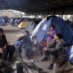 Una familia de refugiados entra en calor junto a una hoguera en el campamento fronterizo griego de Idomeni, en la frontera con Macedonia, hoy
