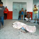 Varias personas observan el cadáver de una persona muerta por una bala durante las protestas en Caracas, ayer