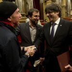 El presidente de la Generalitat de Cataluña, Carles Puigdemont, saluda al diputado de JxSí Lluís Llach (i) en presencia del conseller de Salud, Antoni Comín