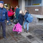 Niños frente a un policía a la entrada de una escuela en Bruselas