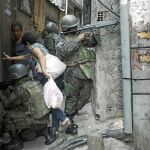 Una mujer cruza entre soldados mientras patrullan en un callejón durante una operación en la favela de Rocinha, en Río de Janeiro