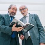 Pedro Muelas, autor del libro, muestra al doctor Mir una de las fotografías que aparecen en el libro