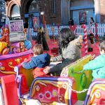 Una familia se monta en una de las atracciones navideñas de León adscritas a la iniciativa «Un kilo, un viaje»