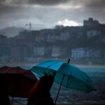 Dos mujeres caminan bajo la lluvia junto a la playa de Ondarreta de San Sebastián | Efe