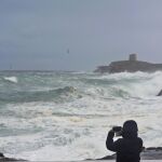 Una persona fotografía la torre de Alcalfar desde S'Algar en el municipio de Sant LLuís, Menorca