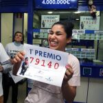 Una joven sonríe con una copia del número 79.140, agraciado con el Gordo de Navidad del Sorteo Extraordinario de la Loteria celebrado hoy y vendido íntegramente en la administracion nº 2 de Roquetas de Mar (Almería)