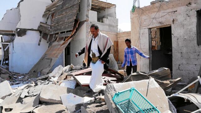 Dos yemeníes caminan entre las ruinas de su vivienda tras los bombardeos de la coalición árabe