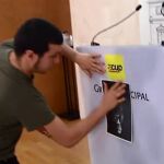 Edgar Fernández pega en el atril la imagen del Rey cabeza a bajo